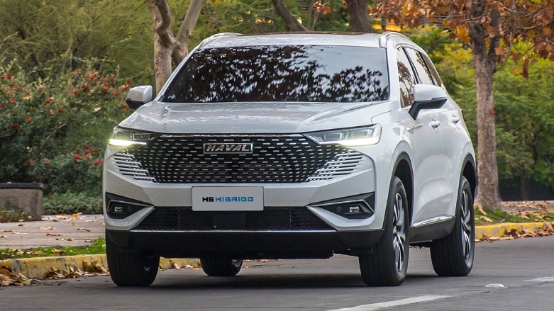 Vista frontal de camioneta HAVAL H6 Hibrido color blanco conduciendo sobre carretera con fondo natural