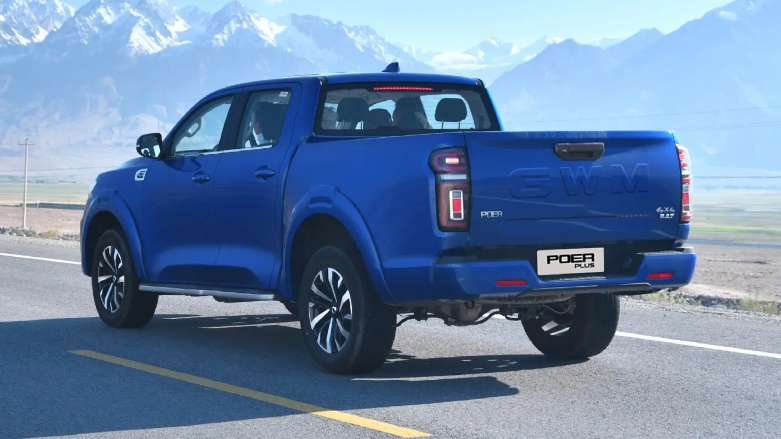 Vista trasera de pick up GWM Peor Plus color azul siendo conducida por carretera con nevado de fondo.